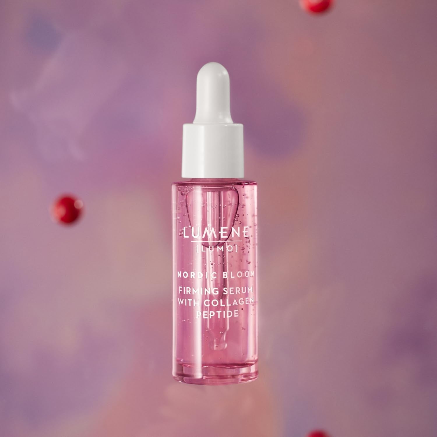 Pink serum bottle with white cap on a blurred purple background