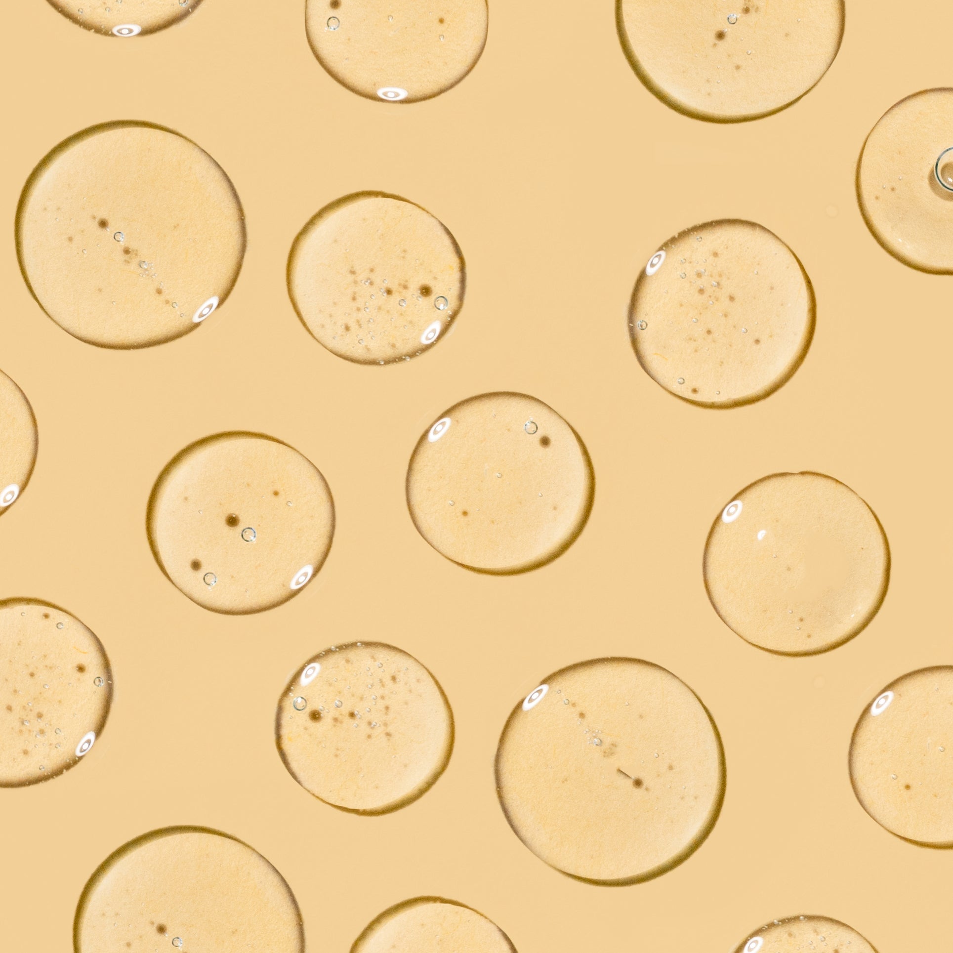 Somme Institute Serum texture close-up - golden serum droplets on beige background showing lightweight anti-aging formula